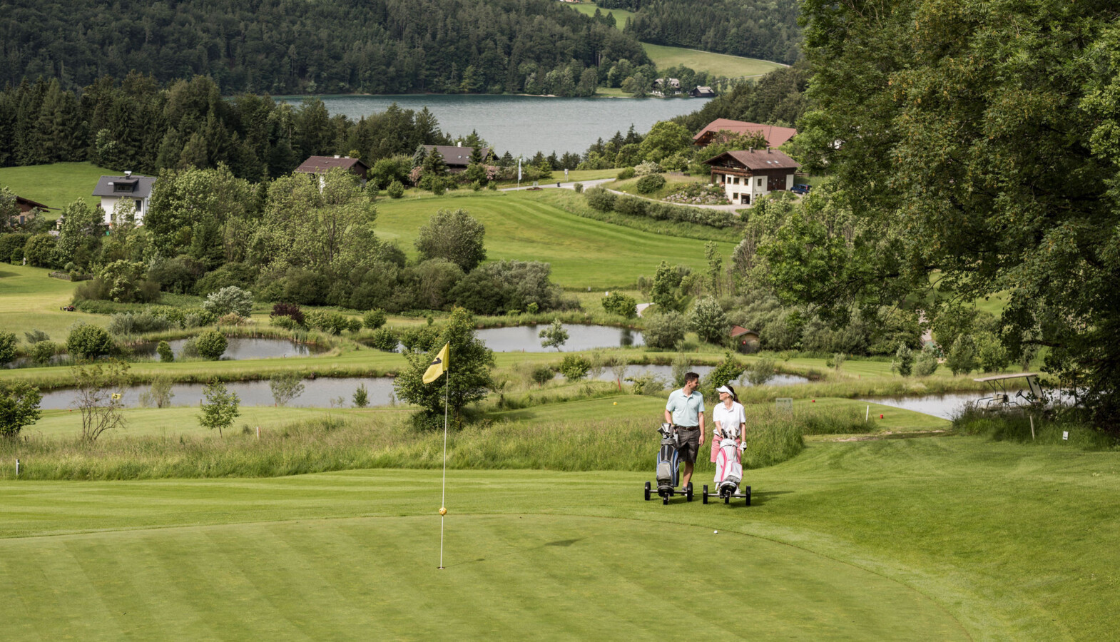 Pärchen auf dem 9 Loch Golfplatz des Golfclub Waldhof mit Blick auf den Fuschlsee.