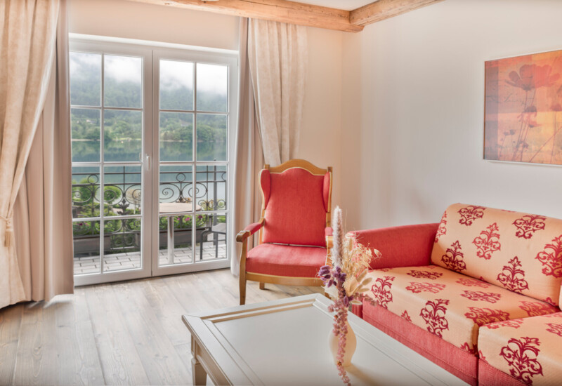 Großzügiges Zimmer mit Balkon und Blick zum See im Hotel Ebner's Waldhof am Fuschlsee.