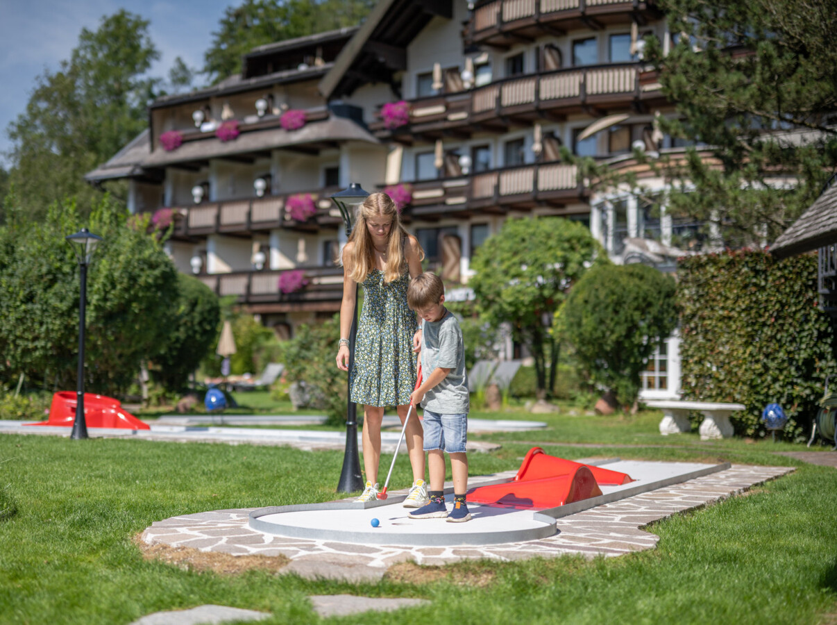 Mutter mit Kind beim Minigolfspielen am hoteleigenen Minigolfplatz im Familienhotel Ebner's Waldhof am See.