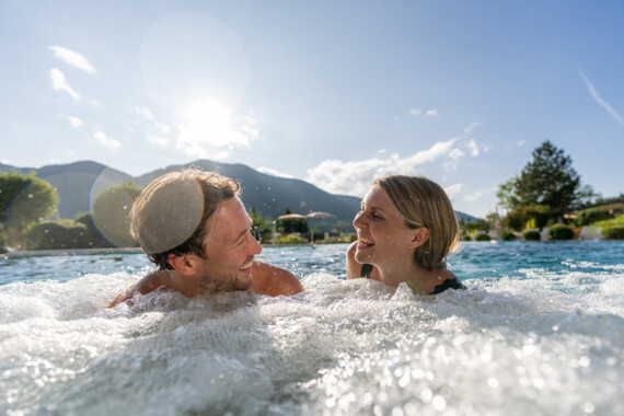 Pärchen beim Schwimmen im Außenpool des Spa Hotel Ebner's Waldhof im Salzburger Land.